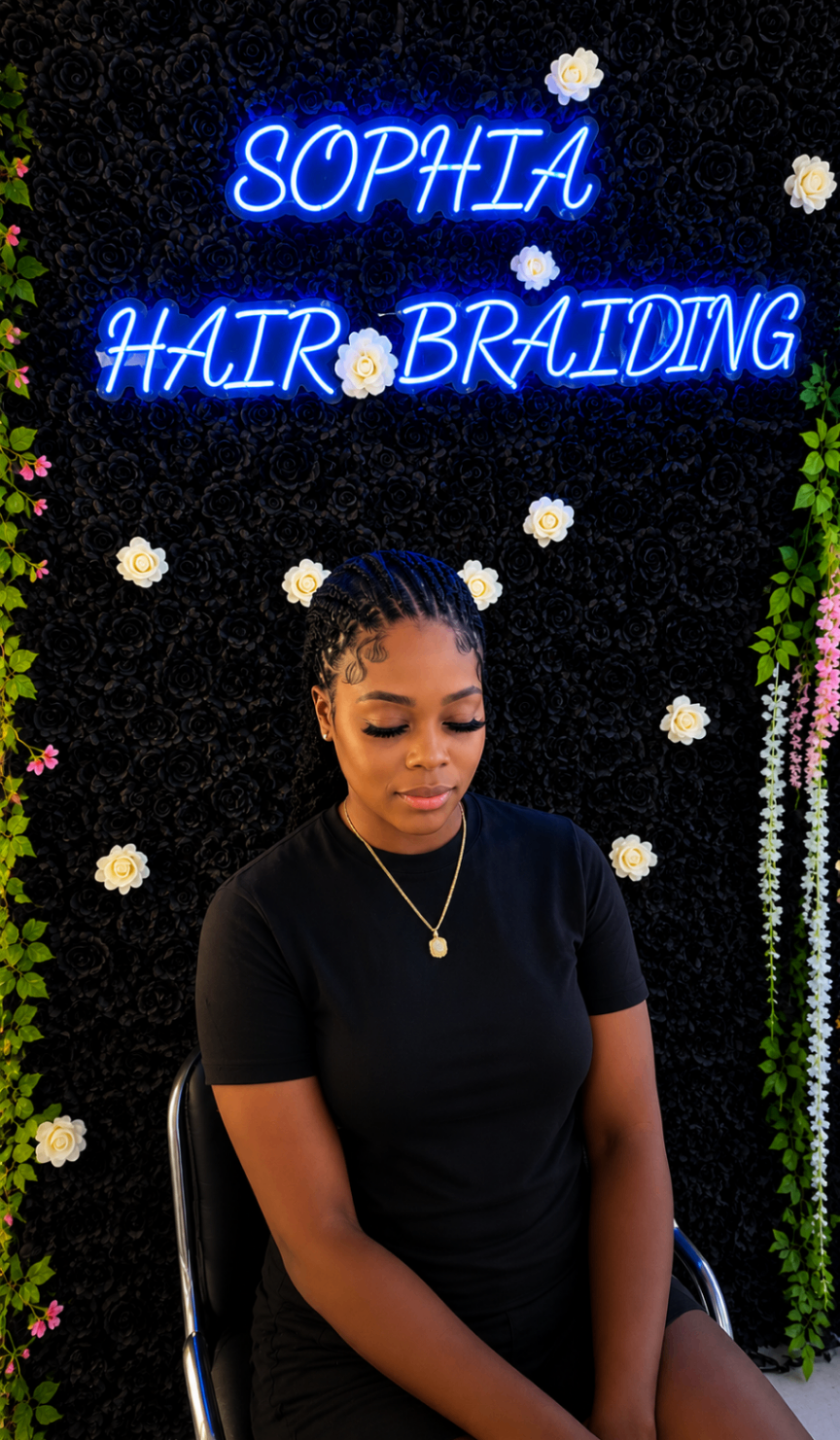 Client with sleek stitch cornrows and edge-styled baby hairs seated under the Sophia Hair Braiding neon sign