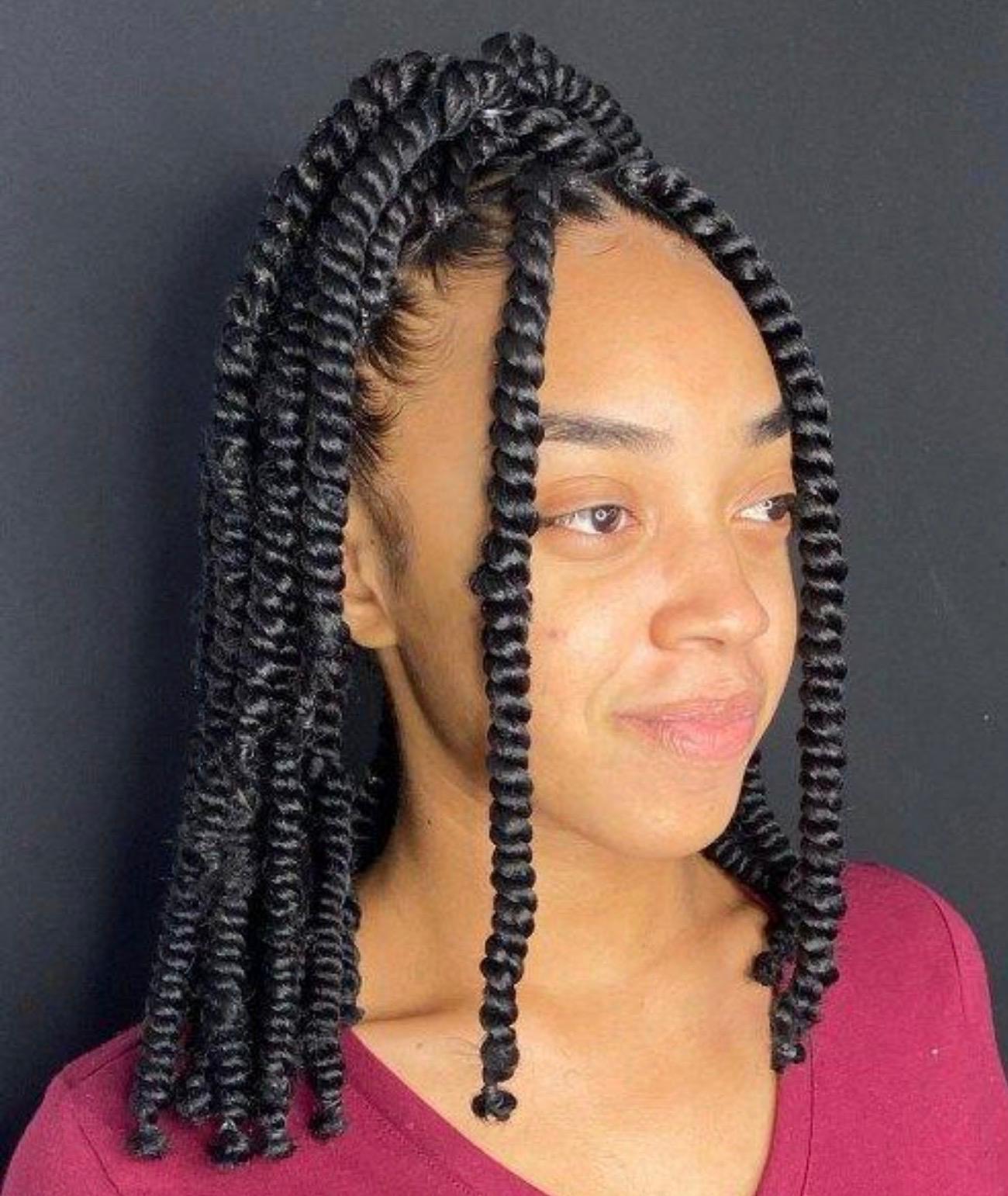 Chunky half-up passion twists with defined coiled ends against a charcoal backdrop