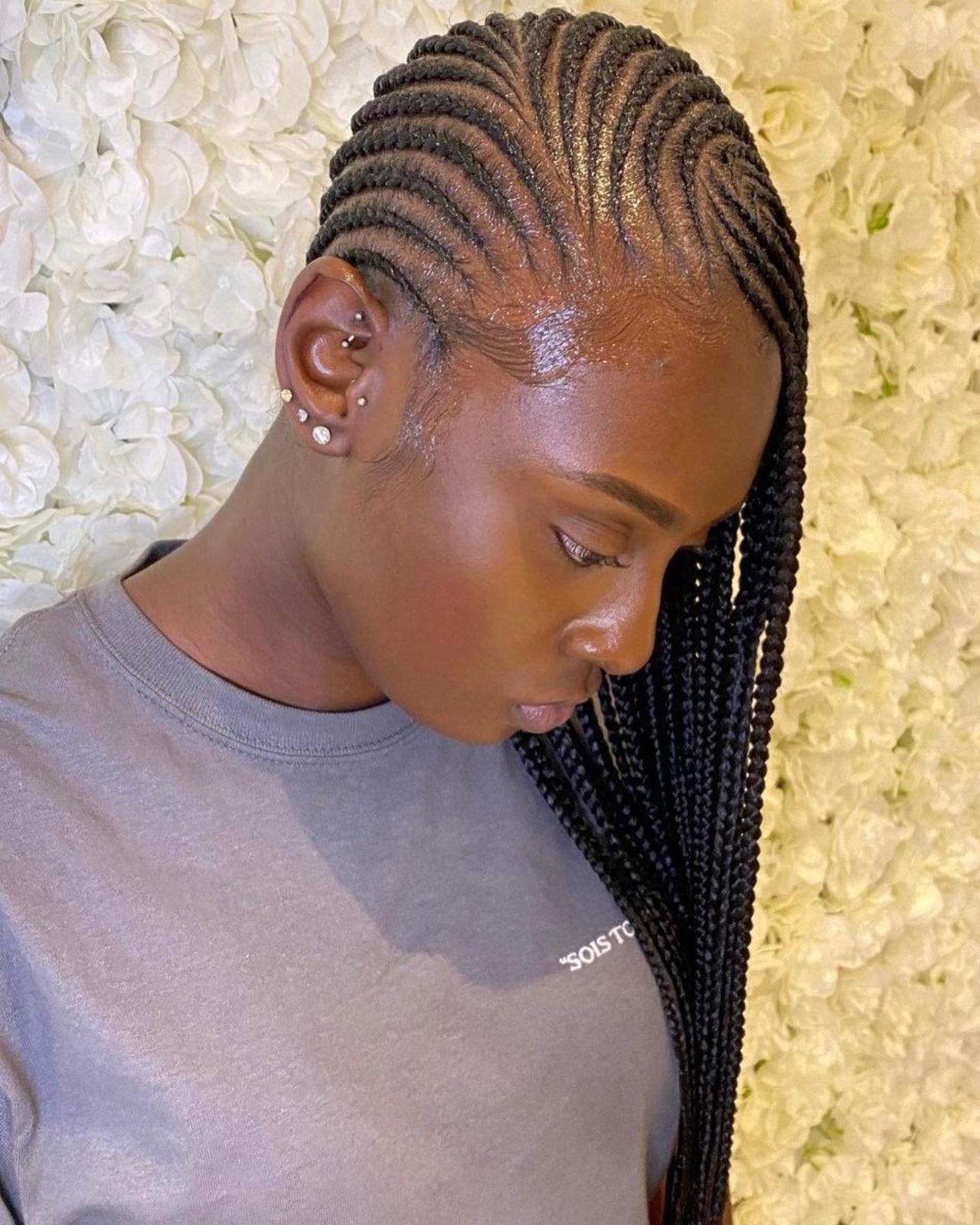 Sleek small feed-in lemonade cornrows braided straight back with laid edges against a white floral wall