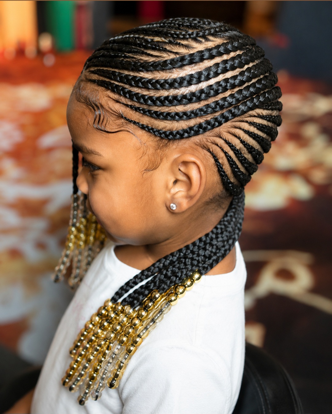 Young girl with intricate feed-in cornrows, laid baby hairs and gold and clear beaded ends styled at Sophia African Hair Braiding Dayton