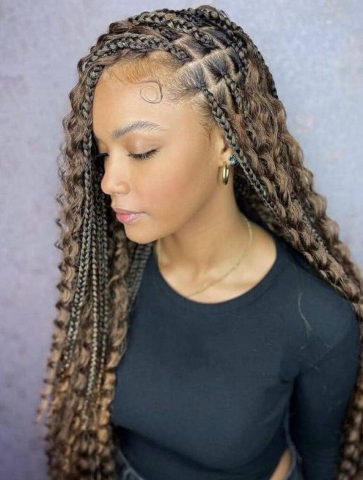 Boho knotless braids with warm honey highlights and curly wavy ends on a client in a black top